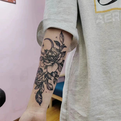 Vertical peony and leaf temporary tattoo with crescent moon on forearm