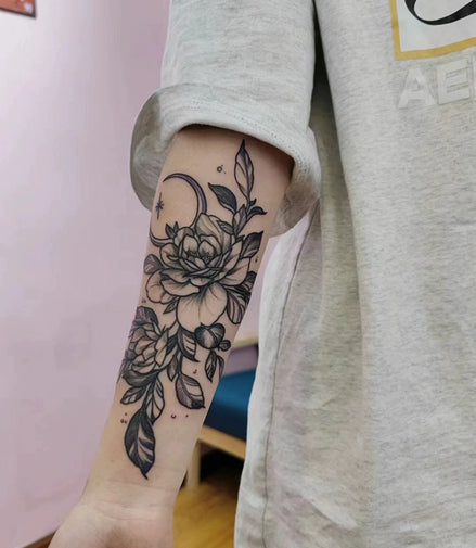 Vertical peony and leaf temporary tattoo with crescent moon on forearm