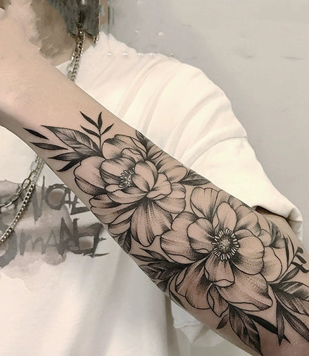 Black-and-grey floral sleeve temporary tattoo with large blossoms and leaves on forearm