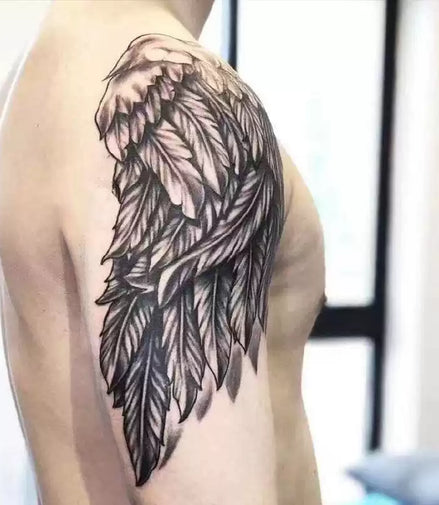 Shoulder temporary tattoo: large angel wing with layered feathers, black-gray shading; skin-safe botanical ink by MysticInk.